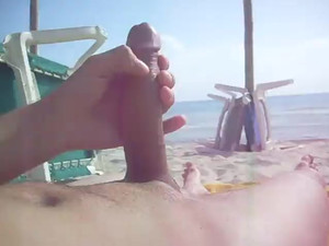 Guy jerking his big dick in the beach