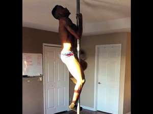 Black masculine stripper spinning on a pole.